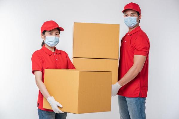 image-of-a-conscious-young-delivery-man-in-red-cap-blank-t-shirt-uniform-face-mask-gloves-standing-with-empty-brown-cardboard-box-isolated-on-light-gray-background-studio-photo